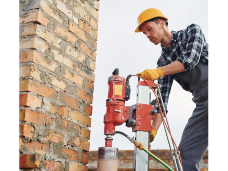 Karot makinesi ile beton delme işlemi gerçekleştiren işçi